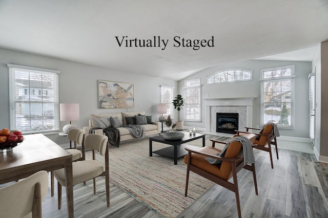 living room featuring a tile fireplace, light hardwood / wood-style flooring, and lofted ceiling