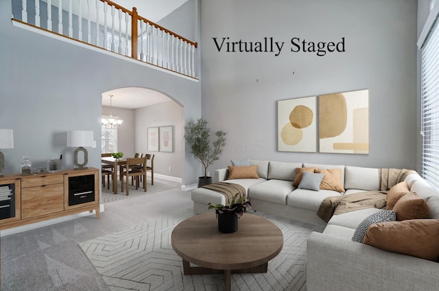 living room featuring a towering ceiling, light colored carpet, and a notable chandelier