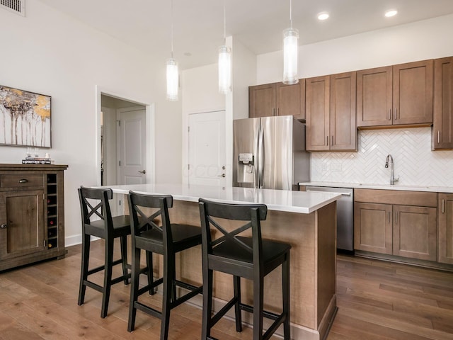 kitchen featuring a kitchen island, sink, decorative light fixtures, and appliances with stainless steel finishes