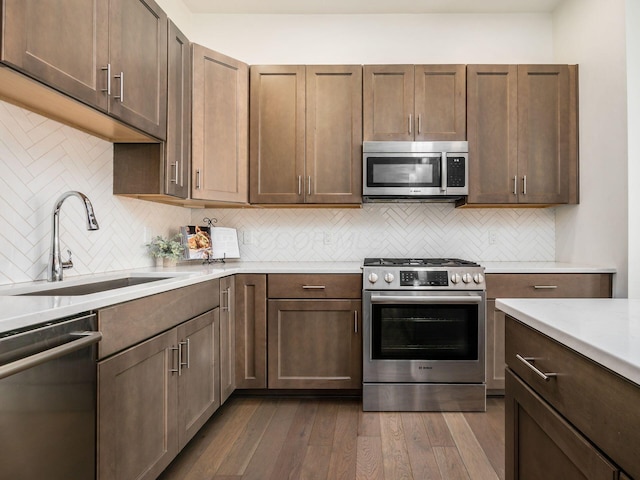 kitchen featuring sink, dark wood-type flooring, tasteful backsplash, and appliances with stainless steel finishes