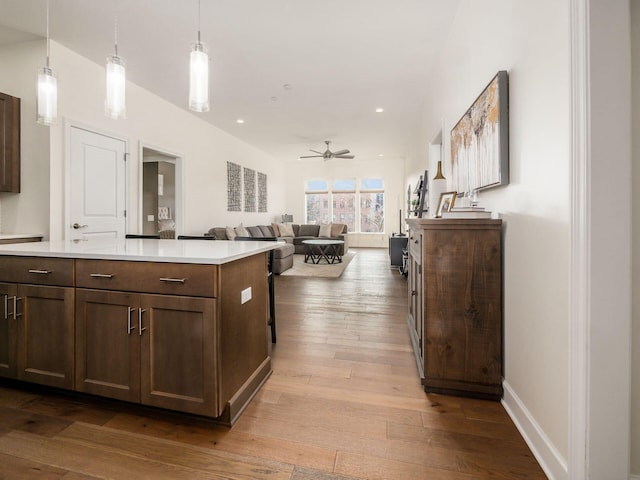 kitchen with a center island, dark brown cabinets, light hardwood / wood-style flooring, pendant lighting, and ceiling fan