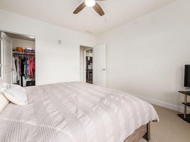 carpeted bedroom with ceiling fan, a spacious closet, and a closet