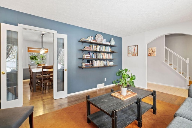 living room featuring french doors, wood-type flooring, and a textured ceiling