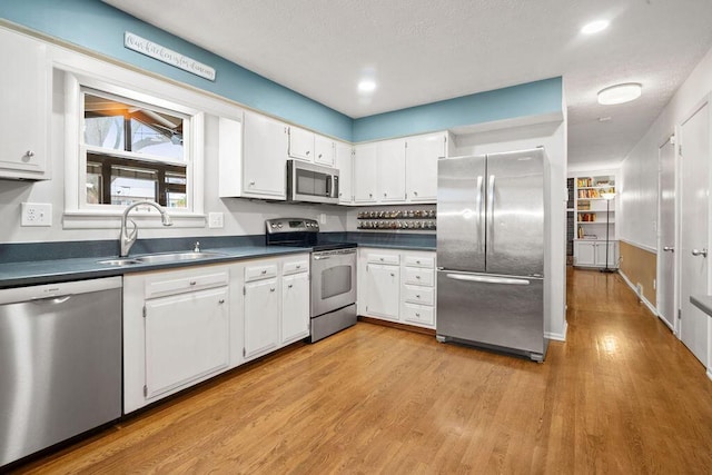 kitchen with light hardwood / wood-style flooring, stainless steel appliances, white cabinetry, and sink