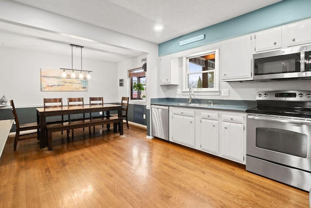 kitchen featuring white cabinetry, stainless steel appliances, and hanging light fixtures