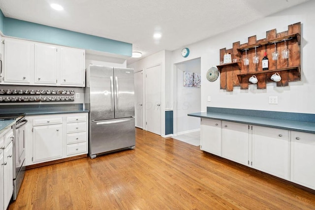 kitchen with white cabinetry, light hardwood / wood-style floors, and appliances with stainless steel finishes