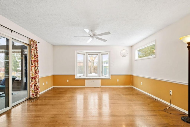 spare room with ceiling fan, light hardwood / wood-style floors, and a textured ceiling