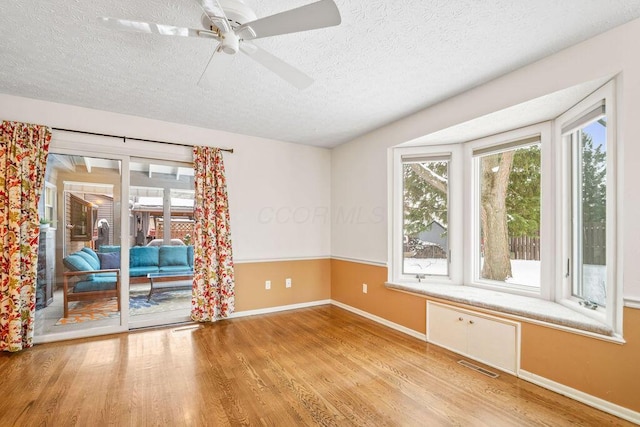 empty room with hardwood / wood-style flooring, ceiling fan, and a textured ceiling