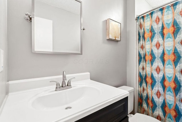 bathroom with walk in shower, vanity, and toilet