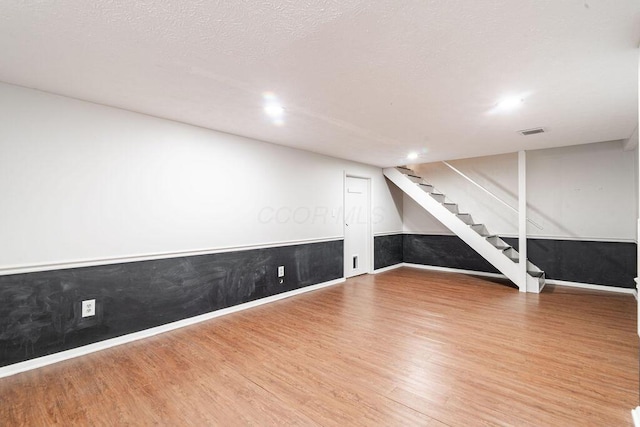 basement featuring wood-type flooring and a textured ceiling