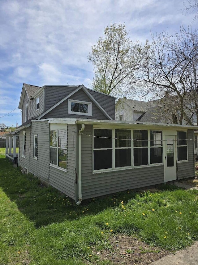 rear view of house with a yard and a sunroom