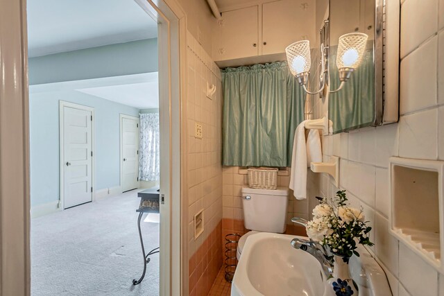 bathroom featuring sink, tile walls, and toilet