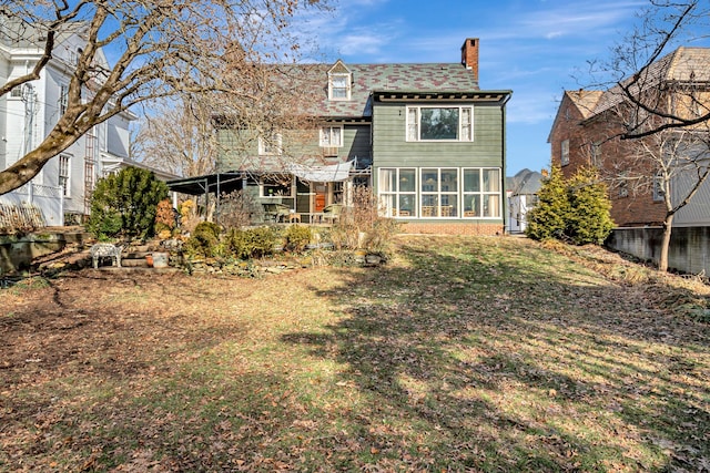 rear view of house featuring a yard and a sunroom