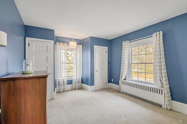 unfurnished bedroom featuring multiple windows, radiator, and light carpet