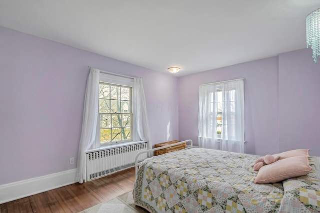 bedroom featuring multiple windows, wood-type flooring, and radiator heating unit