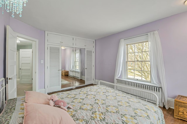 bedroom with hardwood / wood-style flooring, radiator heating unit, and a closet