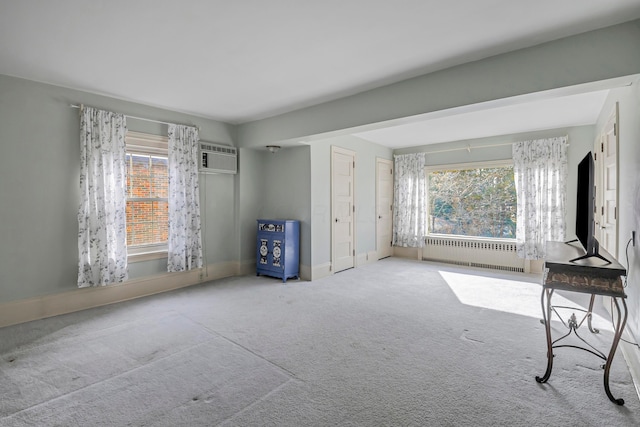 interior space with carpet floors, radiator, and a wall unit AC