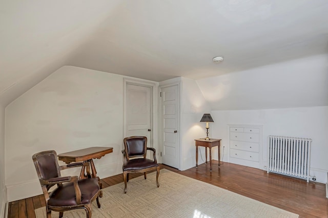 sitting room with hardwood / wood-style flooring, lofted ceiling, and radiator heating unit