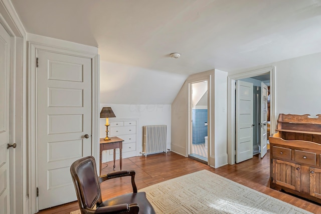 bedroom with lofted ceiling, radiator heating unit, and light hardwood / wood-style flooring