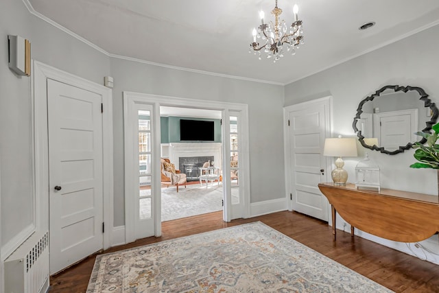 foyer entrance featuring dark hardwood / wood-style flooring, crown molding, and an inviting chandelier