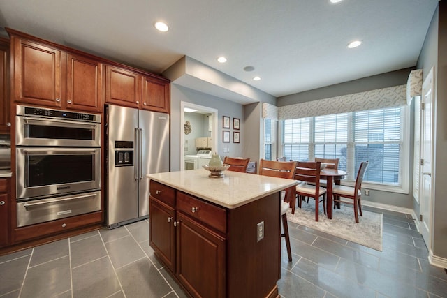 kitchen with light stone counters, appliances with stainless steel finishes, a kitchen bar, and a center island