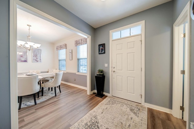 foyer entrance featuring crown molding, hardwood / wood-style floors, and a notable chandelier