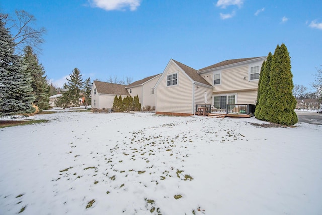 snow covered back of property with a wooden deck