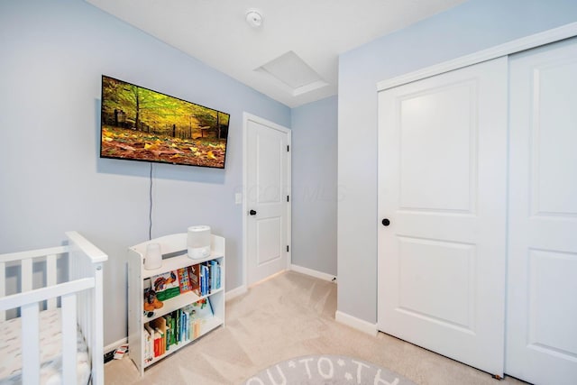 bedroom with light colored carpet, a closet, and a crib