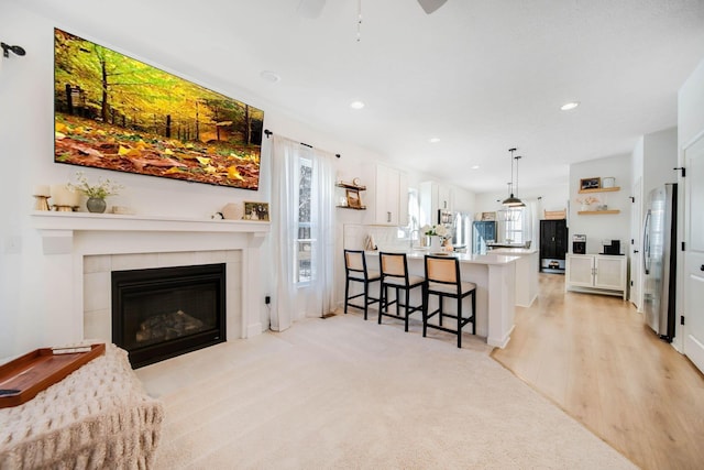 living room with a tile fireplace and light hardwood / wood-style flooring