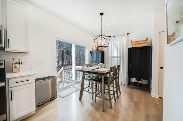 dining space with a healthy amount of sunlight, a notable chandelier, and light wood-type flooring