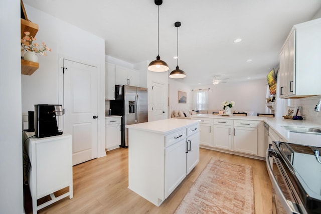 kitchen with white cabinetry, sink, stainless steel fridge, and kitchen peninsula