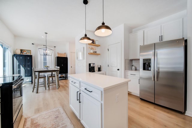 kitchen featuring stainless steel fridge, white cabinetry, range with electric cooktop, tasteful backsplash, and decorative light fixtures