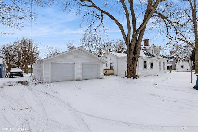 view of snow covered exterior with a garage and an outdoor structure