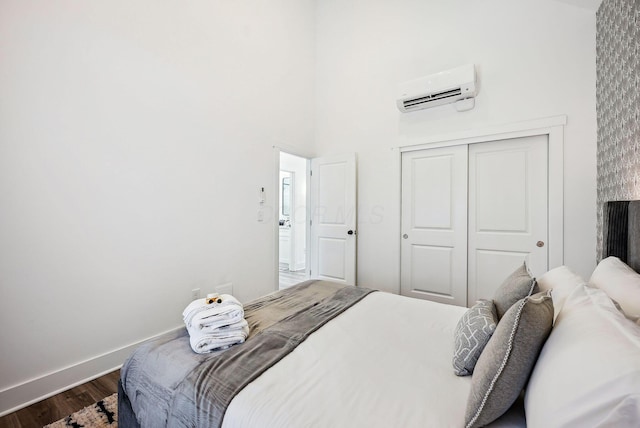 bedroom featuring a closet, an AC wall unit, and wood-type flooring