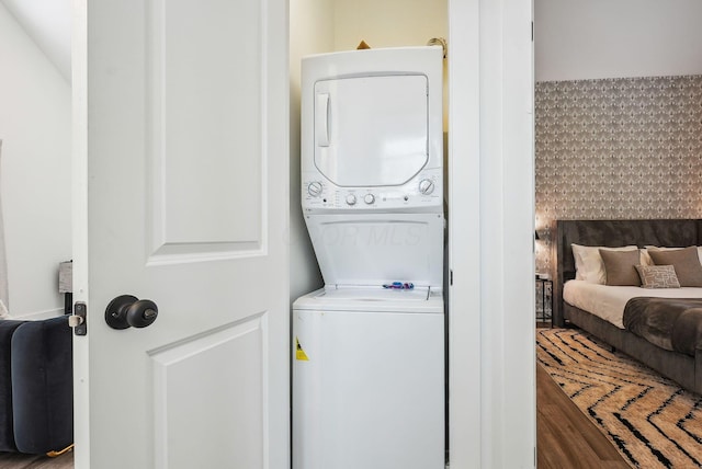 laundry room with hardwood / wood-style flooring and stacked washer and clothes dryer