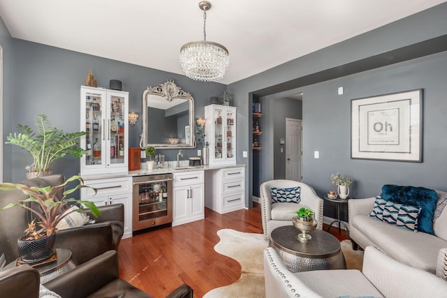 interior space with an inviting chandelier, wine cooler, wet bar, and dark wood-type flooring