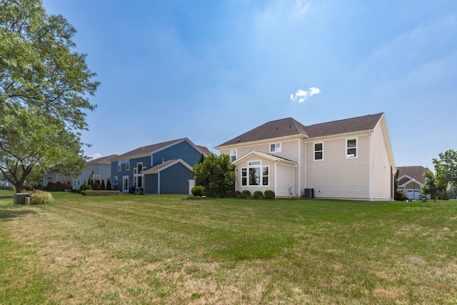 rear view of property featuring central AC and a lawn