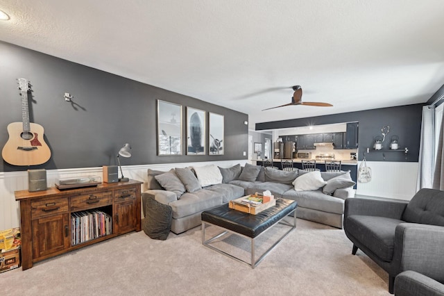 carpeted living room featuring ceiling fan and a textured ceiling