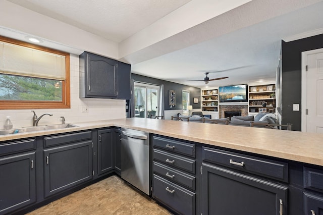 kitchen featuring sink, tasteful backsplash, stainless steel dishwasher, ceiling fan, and a fireplace