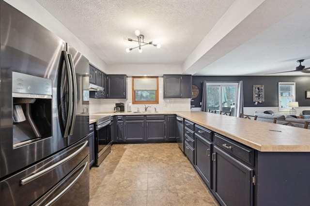 kitchen featuring backsplash, ceiling fan, kitchen peninsula, stainless steel appliances, and a textured ceiling