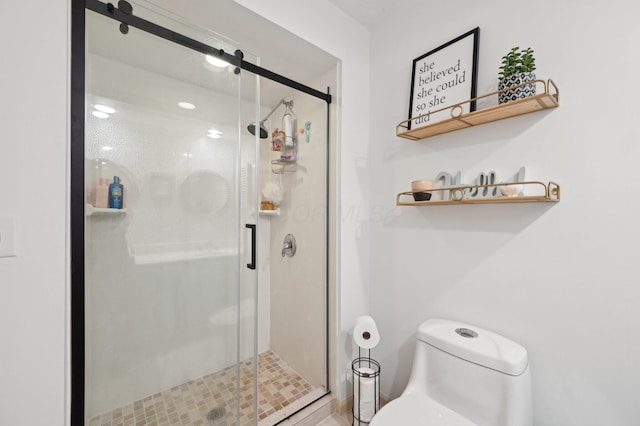 bathroom featuring a shower with shower door and toilet