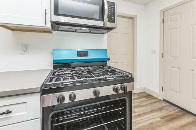 kitchen featuring appliances with stainless steel finishes, light hardwood / wood-style floors, and white cabinetry