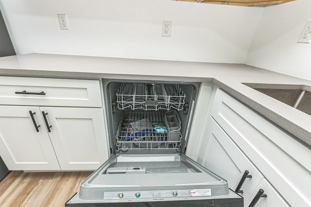 room details featuring white cabinets, light wood-type flooring, and dishwashing machine