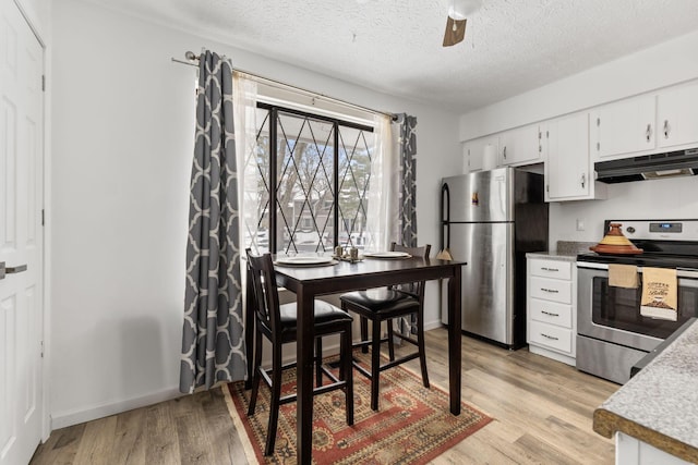 kitchen featuring white cabinets, light wood-type flooring, a textured ceiling, and stainless steel appliances