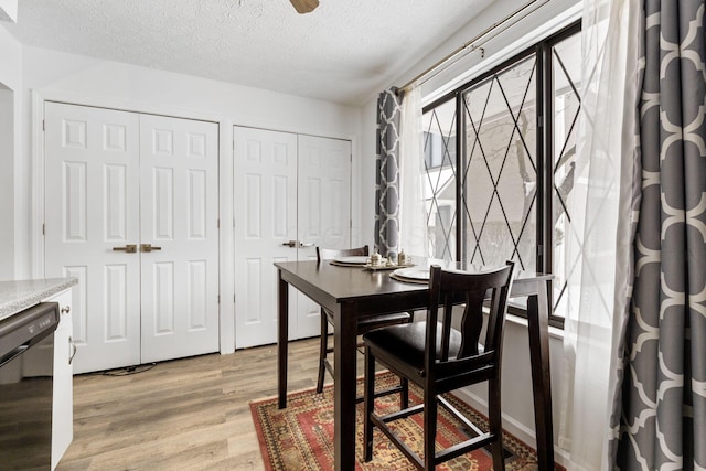 dining area with a textured ceiling and light hardwood / wood-style floors