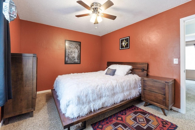 carpeted bedroom with ceiling fan and a textured ceiling