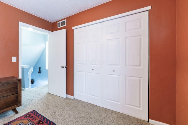 unfurnished bedroom featuring carpet, a textured ceiling, and a closet