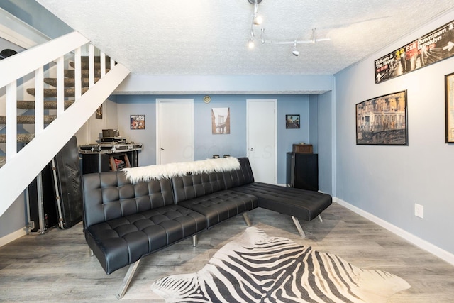 living room with rail lighting, light hardwood / wood-style floors, and a textured ceiling