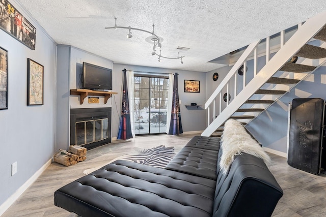 living room featuring rail lighting, a textured ceiling, and hardwood / wood-style flooring