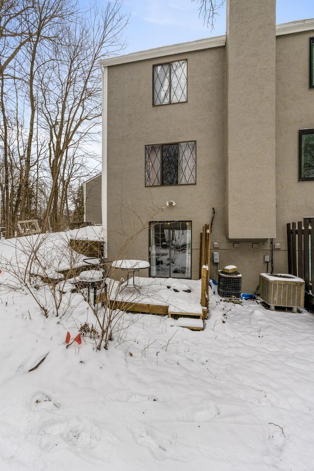 snow covered back of property featuring central AC unit